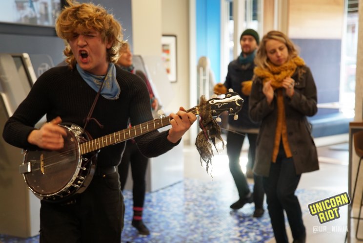 Student plays the banjo and sings while others dance, clap, stomp, sing along.