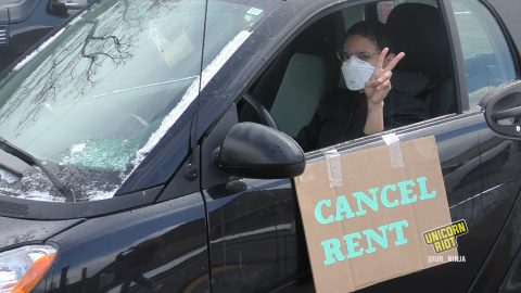 a peace sign is shown by a person with a "cancel rent" sign on their car