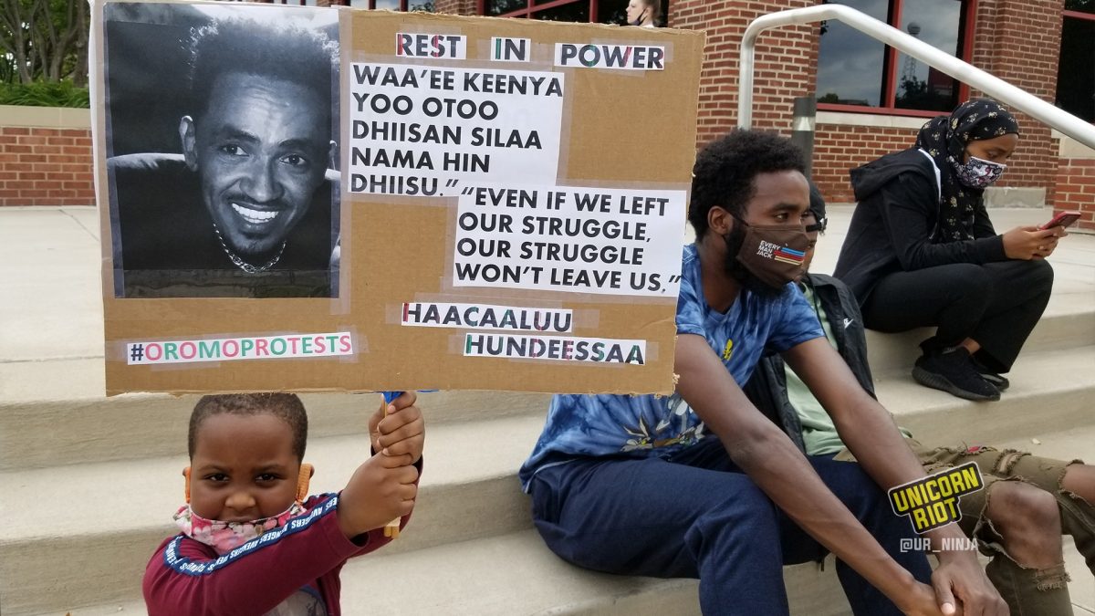 Very young child holds Rest in Power Hundessa sign