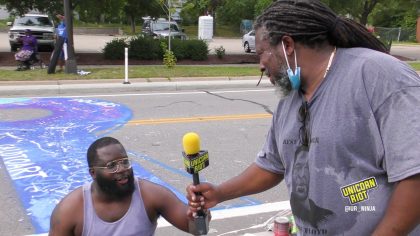 Charles Caldwell passes the mic to his son Charles after painting the R* in Black Lives Matter mural in Minneapolis