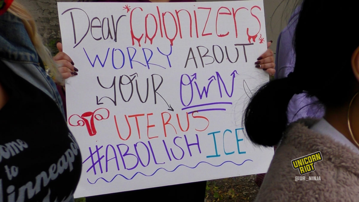 Sign reads: Dear colonizers, worry about your own uterus. #AbolishICE