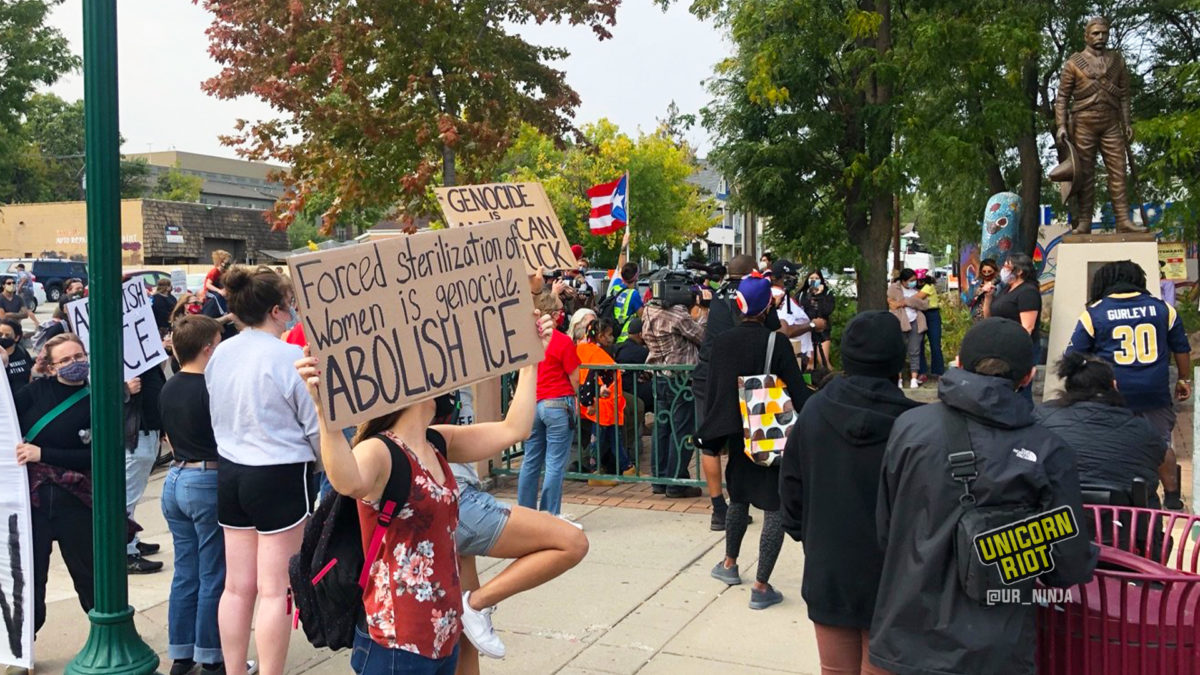 protesters hold signs against forced sterilizations in ICE facilities