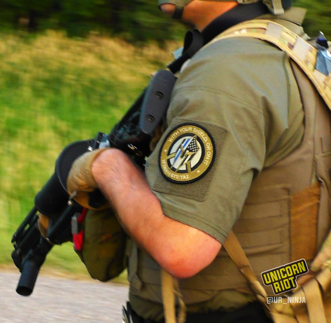 a responding officer with a blue line patch that says "with your shield, or not" 