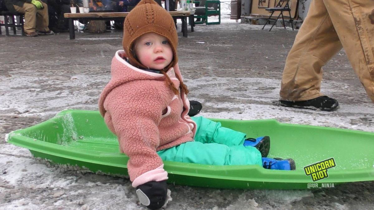 Young child in a sled being pulled through the parking lot of the People's Way in George Floyd Square