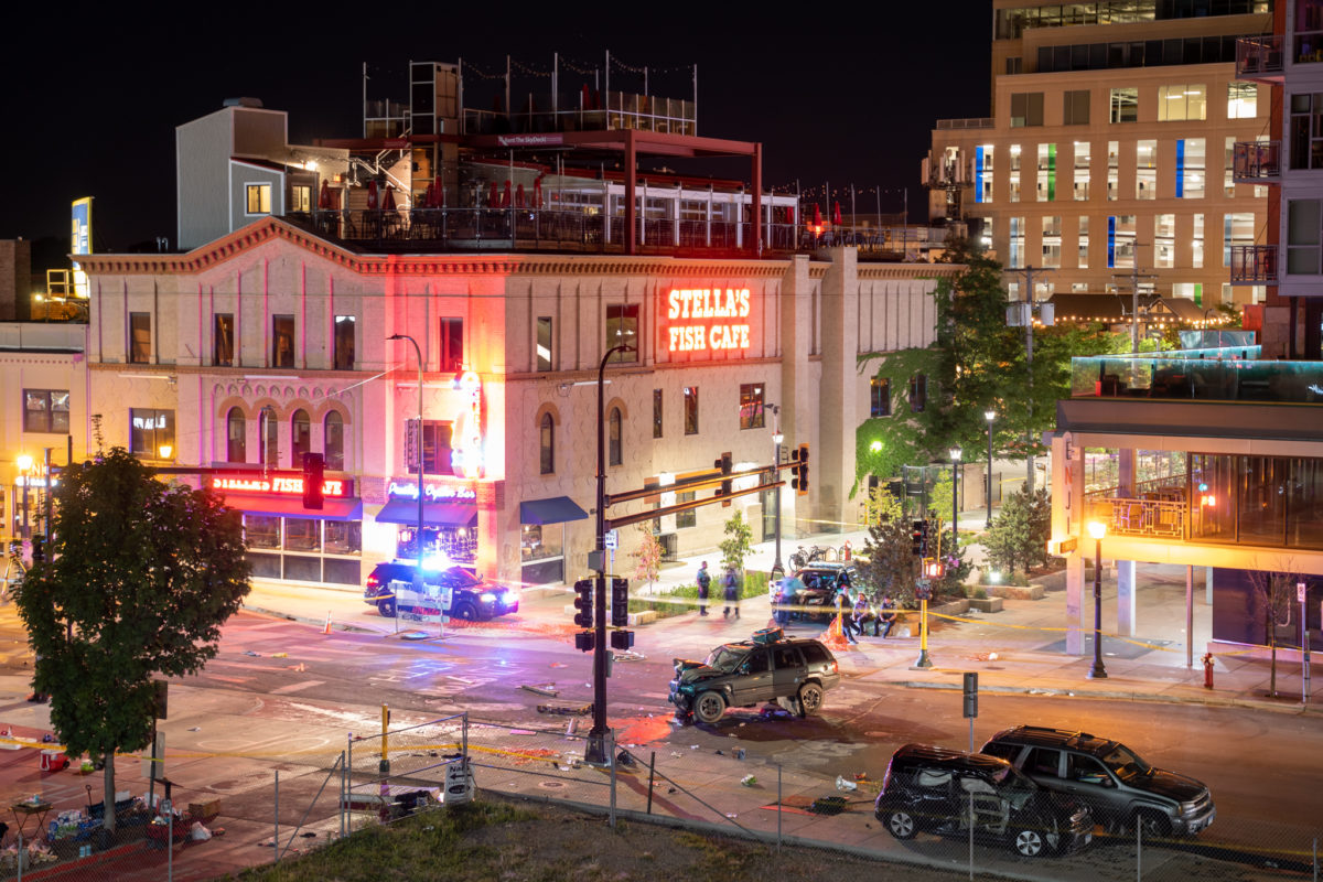 The scene of the car attack by Nicholas Kraus that killed Deona Marie. The driver’s smashed Jeep Cherokee sits in the middle of the intersection after smashing Deona’s black Kia into her, killing her – The Kia was parked on the far left of the image above before being hit head-on. Two police cars are in background and scene is taped off.  – image via @daviss