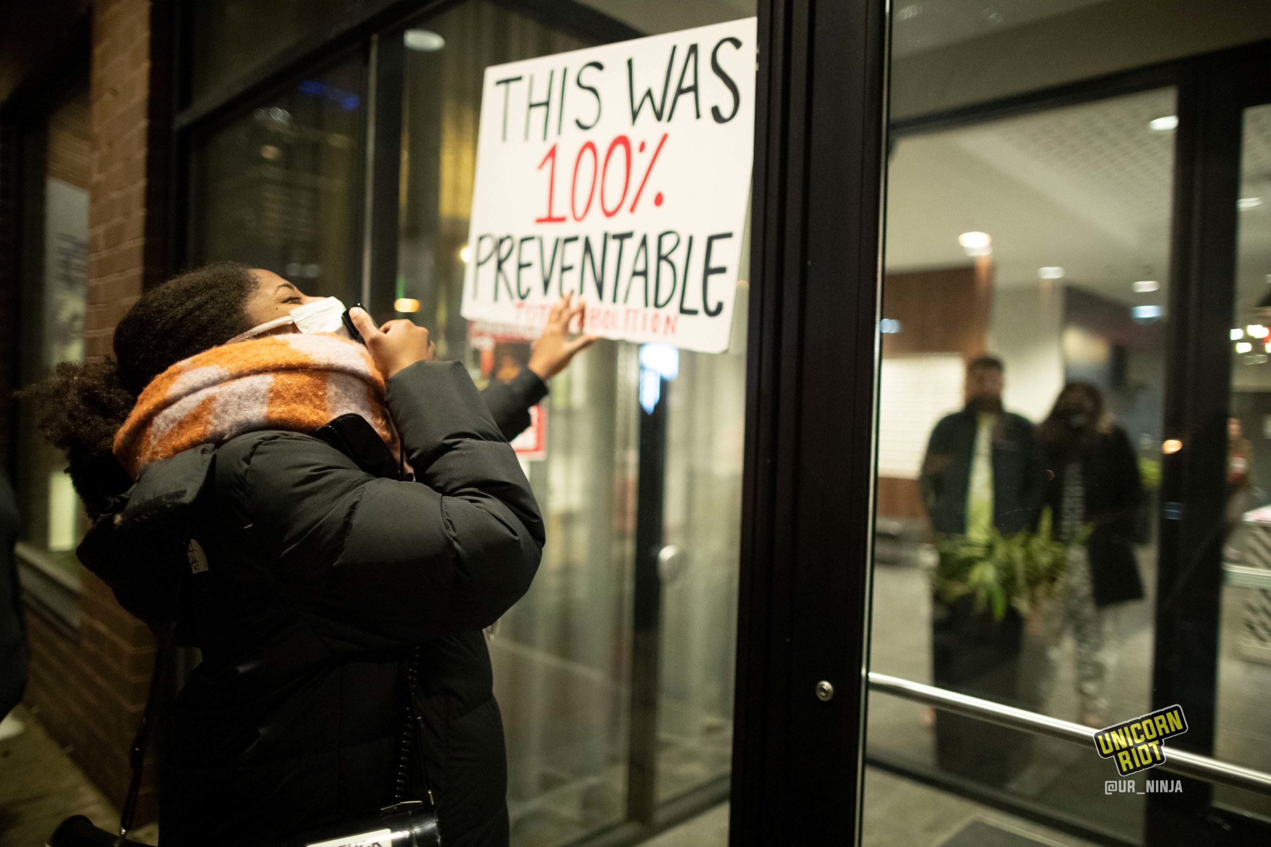 February 8, 2022, Minneapolis, Minnesota, USA: Screaming into a megaphone, a women shouts as she stands outside of the Bolero Flats Apartments. She holds a sign that reads "This was 100% Preventable - total abolition." On February 2, 22 year old Amir Locke was killed by Officer Mark Hanneman of the Minneapolis Police.