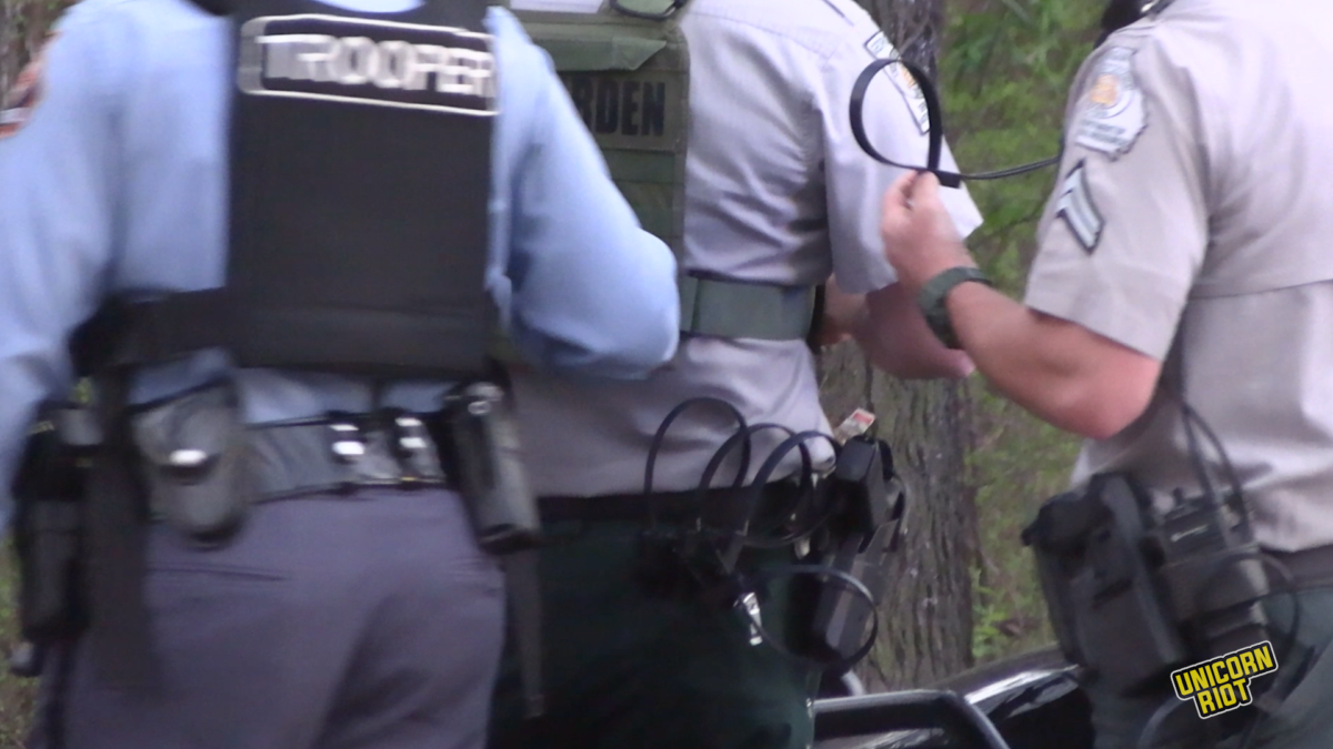 A shot from behind shows Georgia State Troopers and DNR wardens holding black plastic ziptie handcuffs before making arrests at the music festival in the South River Forest near Atlanta on March 5, 2023. 