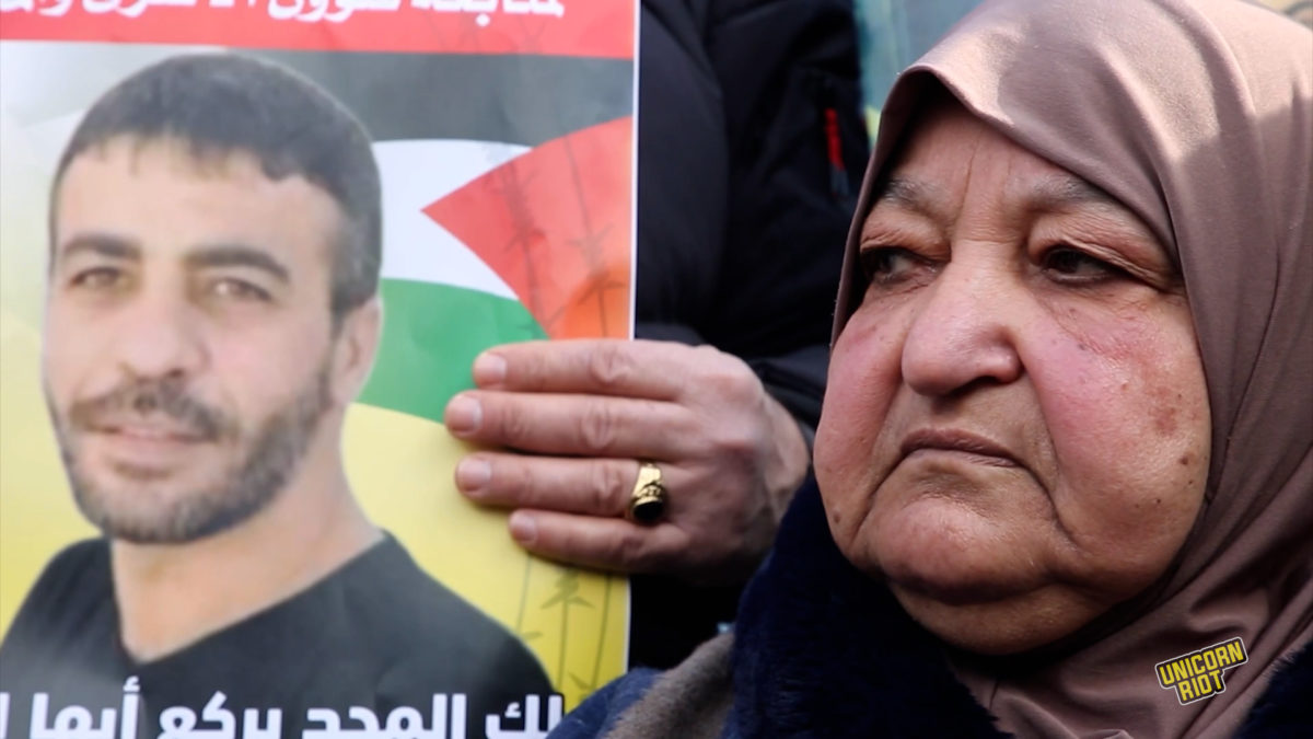 mother of nasser abu hamid sits as someone holds an image of her son during a march