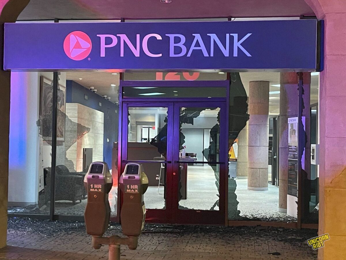 A PNC Bank location with its front windows and door glass smashed to shit

