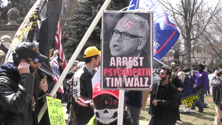 sign saying "arrest psychopath tim walz" with swastika on walz image